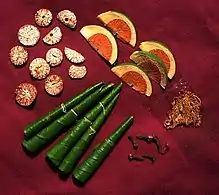 Display of the items usually included in a chewing session: The betel leaves are folded in different ways according to the country and most have a little calcium hydroxide daubed inside. Slices of the dry areca nut are on the upper left hand and slices of the tender areca nut on the upper right. The pouch on the lower right contains tobacco, a relatively recent introduction.