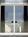 Entrance 'L' at the palazzo. In the reflection of the door the Colosseo Quadrato can be seen reflected.