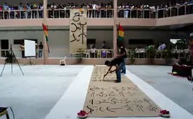 Man writing on a large sheet of paper on a floor