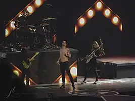 Panic! at the Disco at the Pepsi Center in 2018From left to right: Kenneth Harris (guitar), Dan Pawlovich (drums), Brendon Urie (vocalist), and Nicole Row (bass)