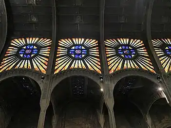 Stained glass windows in sunburst design over the side aisles of nave