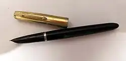 An image of a black Parker 51 fountain pen with a gold cap, which has been removed and placed beside it. The background is white.