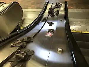 A set of escalators with bronzed gloves scatted in the area between the two.
