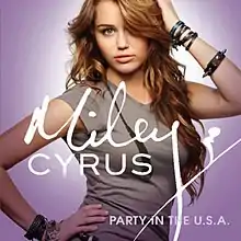 Cover art for "Party in the U.S.A.": Miley Cyrus against a lavender background, wearing a grey shirt and long, curly, brunette hair