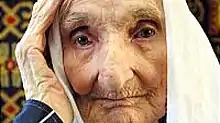 Photograph of an elderly, pale-skinned woman with a white headcovering.