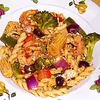 A pasta salad with shrimp, chicken and vegetables