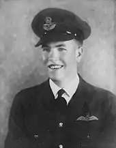 Studio portrait of young man wearing dark military uniform with pilot's wings and peaked cap