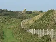 Kenfig Castle, the top of the keep is all that emerges from the dunes of Kenfig Burrows
