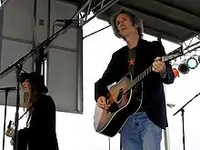 Smith singing with a guitar and Kaye playing guitar onstage