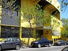 Yellow, multi-story building with cars parked in front