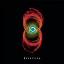 In a black background is the image of a nebula, which resembles two orange rings of smoke, with an eye-like structure in their intersection. Below it is the title "BINAURAL" in white letters.