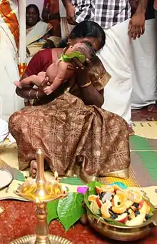 Image 2A new born's Namakarana ceremony. The grandmother is whispering the name into the baby's ear, while friends and family watch. (from Samskara (rite of passage))