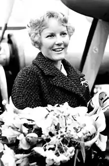 A young blonde woman holding a large bunch of flowers