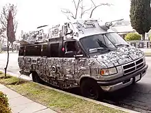 A parked van decorated with electronics and spray painted silver.