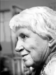 An older woman with olive skin and short white hair, photographed in profile
