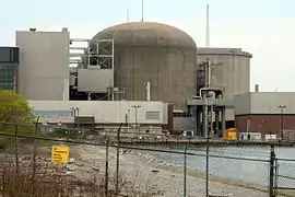 A single unit of the Pickering Nuclear Generating Station, showing a slightly different shape from a typical PWR containment, which is mostly due to the larger footprint required by the CANDU design. The vacuum building can be seen partly obscured on the right.