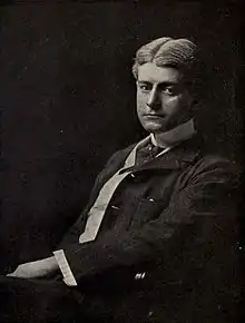 A photograph of a seated Frank Norris, wearing a casual suit and sporting parted hair