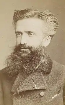 Portrait of a man in his thirties with swept back hair and a large beard