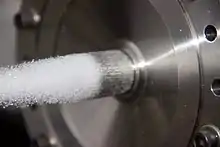 A pintle injector is shown during a cold flow test. The outer flow path is active.