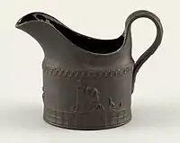 Small elliptical jug in black basalt ware (glazed inside), with sprigged Neoclassical reliefs.