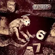 A monkey with a halo over its head and blocks reading "5", "6", and "7" around him`