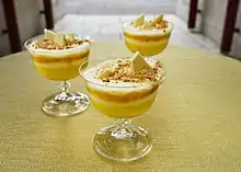 Several glasses containing yellow and white layered trifle