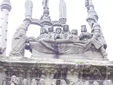 The "Mise au tombeau" on the east face of Pleyben's calvary. In a sombre scene Jesus' body is prepared for burial in the tomb.