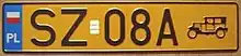 Yellow orange plate reading SZ08A. A vintage car symbol is visible next to the number. Polish national flag is in the top-left corner