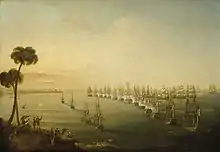A broad view of a bay. Running vertically from the foreground to the background is a line of 14 anchored ships flying red, white and blue tricolour flags. to their left are four more anchored ships and to the left of these vessels is a distant shoreline. In the foreground of this shore is a hillside on which several men in turbans watch the scene below. To the right of the line a number of ships with all sails set are grouped around the head of the line, as smoke rises from many of the ships on both sides.