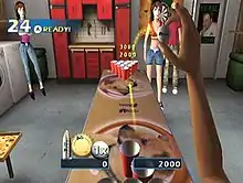 A screenshot of a game, depicting the player's character playing beer pong; they are about to throw a ping pong ball in a first-person perspective in order to land it in one of multiple red cups while people watch.