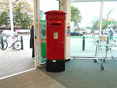A glass-fibre type PB58 pillar box of the type frequently seen in British supermarkets, made by Broadwater Mouldings Ltd of Eye, Suffolk.