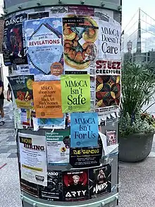 Community members' posters in front of MMoCA in August 2022. Signs in support of the Triennial artist collective reading "MMoCA isn't safe," "MMoCA doesn't care about Black Art, Black Women, Black Community," "MMoCA Doesn't Care," and "MMoCA Isn't For Us,"". MMoCA's glass facade and iron staircase are visible in the background.