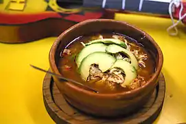 Pozole topped with sliced avocado