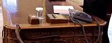  a close-up view of the resolute desk showing the Presidential call button and the HMS Gannet pen holder.