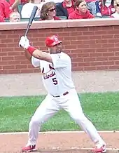 A man with feet spread apart holding a baseball bat in the air