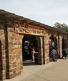 Orange sign reading "Pumpkins in the Park" in the archway of a stone building