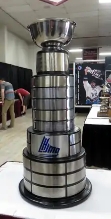 Tall and slender trophy with a silver cup atop of multiple rings of nameplates