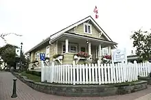 the Thrall residence, a yellow house with a white picket fence.