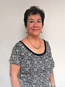 Three-quarter photo of a woman in a black and white scoop-neck t-shirt with a floral print wearing silver earrings and a silver necklace.