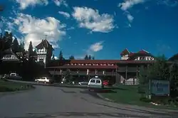 An ornate two-story building with a central clock tower and red roof in the rear of the left side of the image. On the right is a large sign in the foregrounds with "Redstone Inn" in large gothic letters, "Historic Landmark" in smaller type above it, and "Restaurant & Bar" below