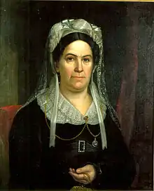 Woman in black with white bonnet and lace collar looking forward