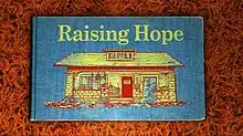 The cover of a blue storybook, with the words 'Raising Hope' written in yellow above a picture of a house.