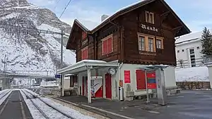Two-story building with gabled roof; snow has fallen on the platforms