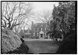 black and white photo of a two and a half-story brick colonial home with wing on left