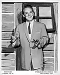 Red Foley standing in front of a window on a set