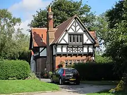 A house in Tudor Revival style with a brick lower storeys and a gabled timber-framed upper storey