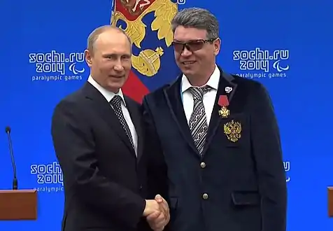 Valerii Redkozubov poses and shake hands with Russian President, Vladimir Putin after medal success