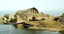 A reed house in the marshes of Basra Province, southern Iraq in 1978. The shkinta is based on such reed structures.