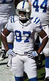 A dark-skinned man wearing a white football jersey and helmet