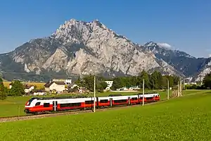 Red-and-white train passing a mountain